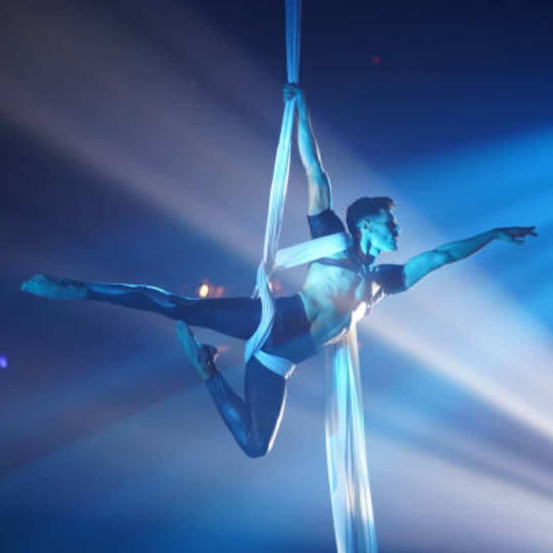 Aerial silk performer under blue lights in Southeast Asia Aerial silk performer under blue lights in Southeast Asia
