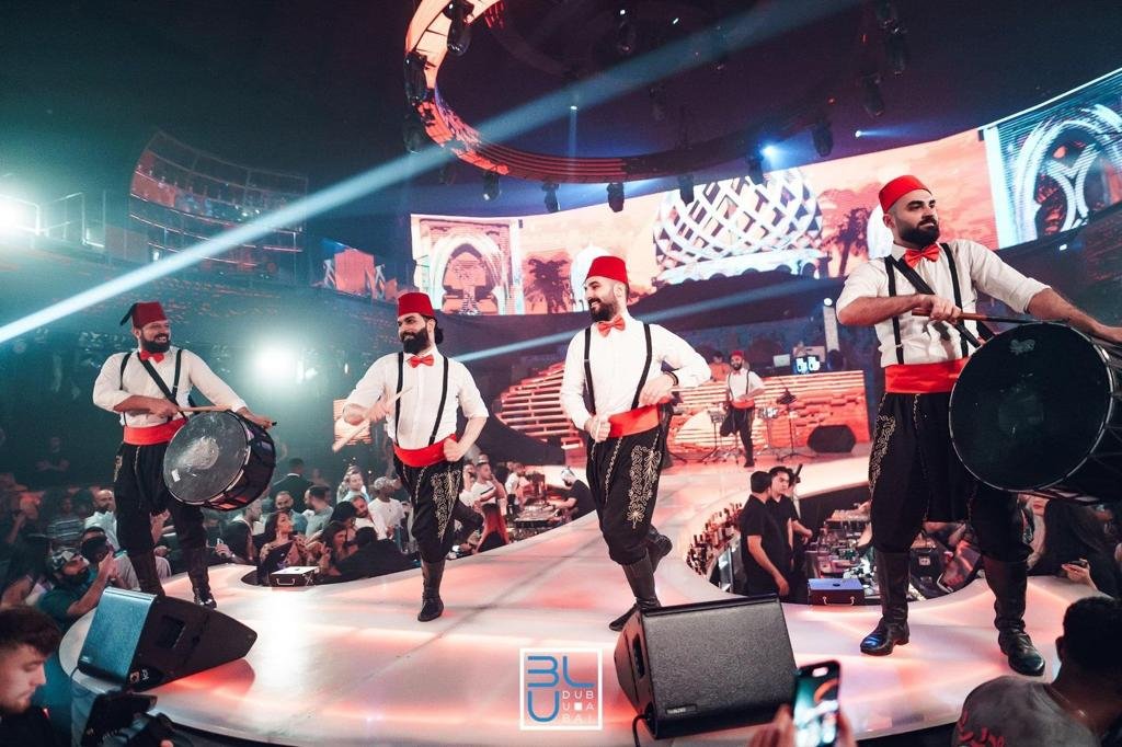 Dabke dancers in red fez hats performing on stage Dabke dancers in red fez hats performing on stage
